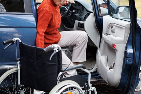 Photo of lady getting out of a car and into a wheelchair